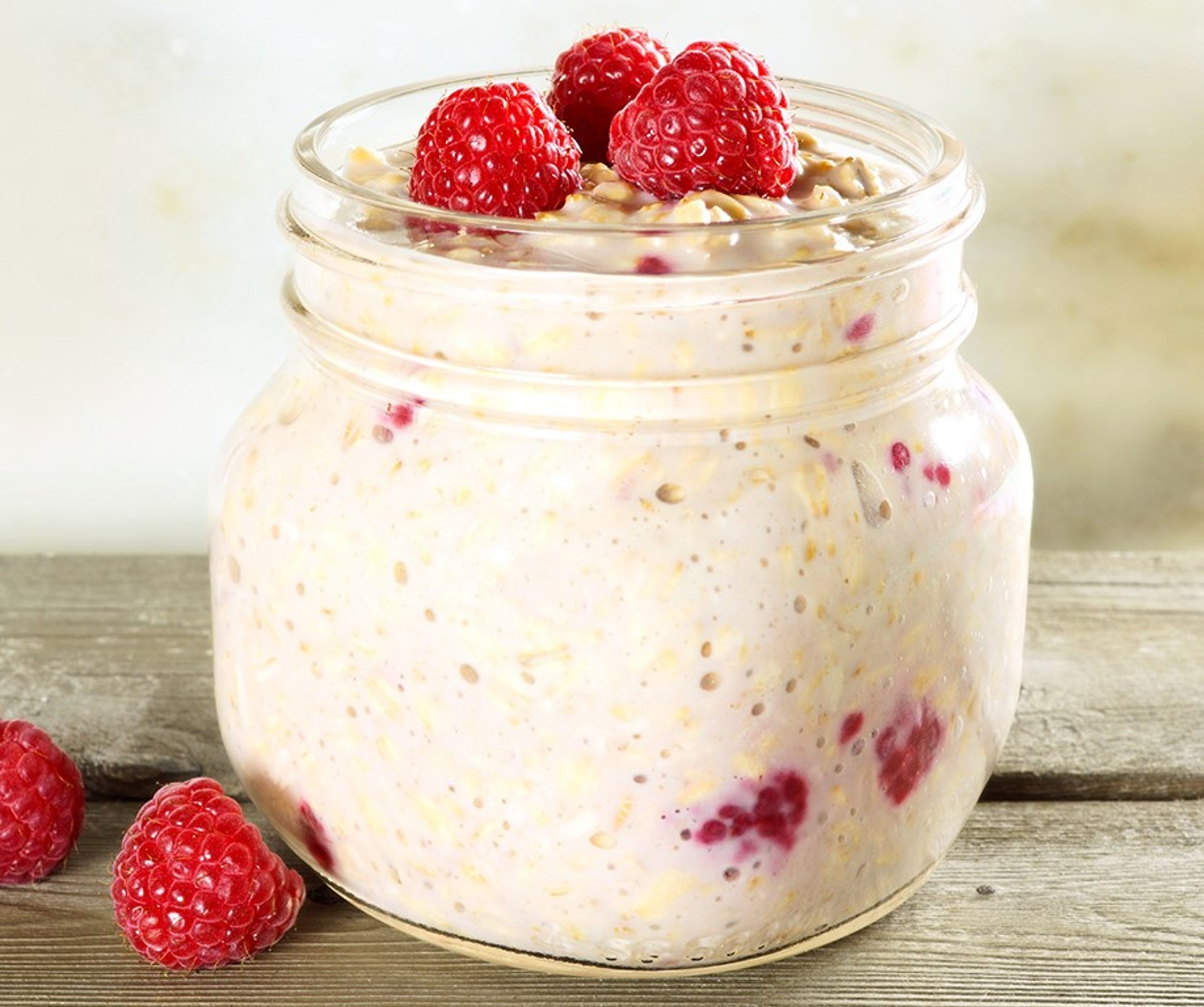 Bocal de overnight oats aux framboises et graines de chia sur une table en bois