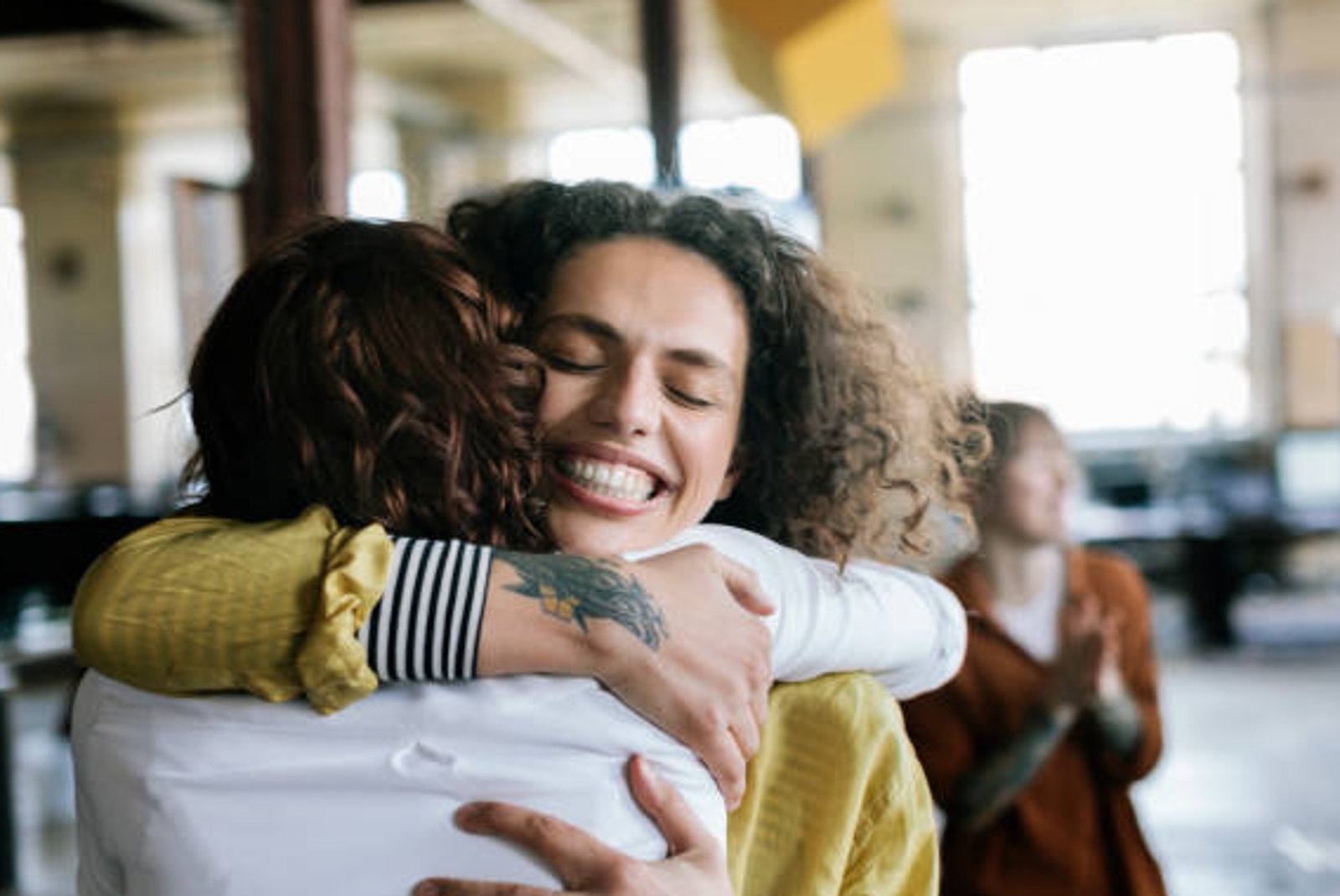 Deux femmes s'étreignant avec joie et souriant dans un espace intérieur lumineux