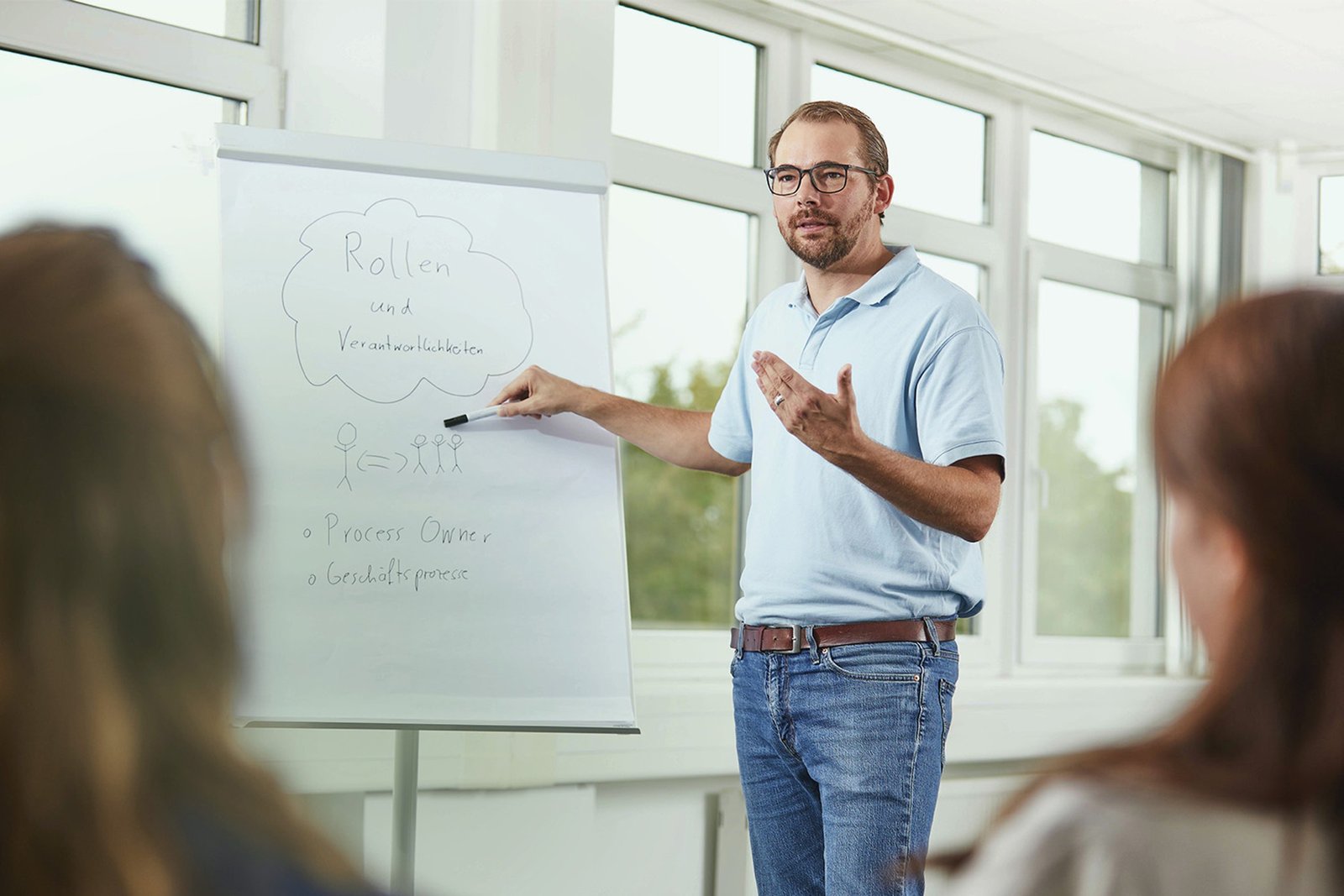 Un homme faisant une présentation devant un tableau blanc, symbolisant la formation, le développement professionnel et le partage des connaissances pour une croissance durable de l'entreprise. Met en avant l'engagement en faveur de l'éducation.